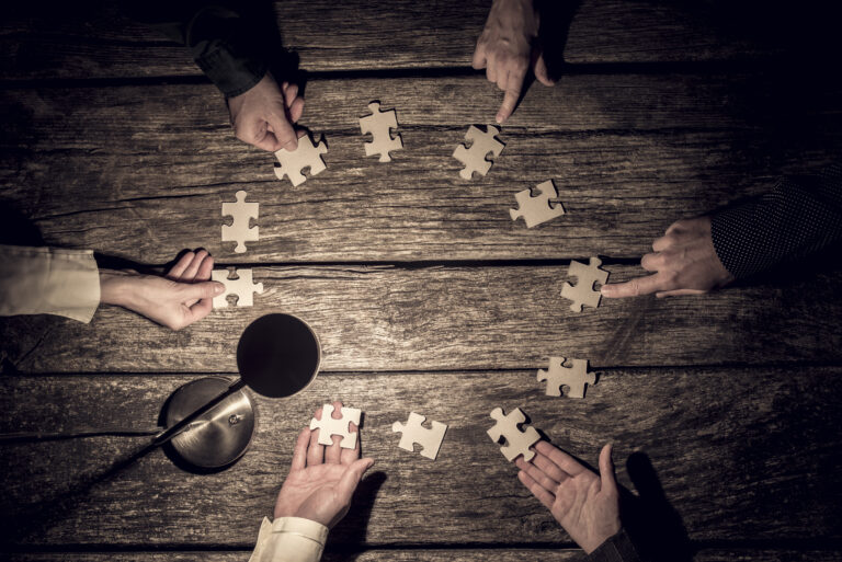 Six business partners placing puzzle pieces in a circle