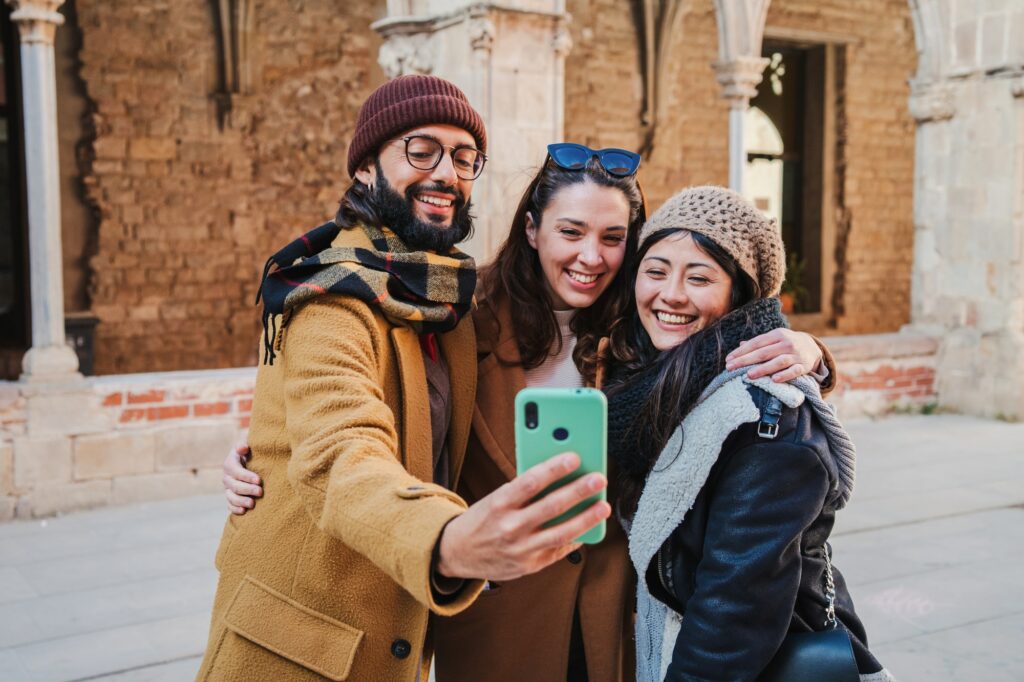 Group of smiling turists friends taking a selfie portrait with a cellphone together to share in the