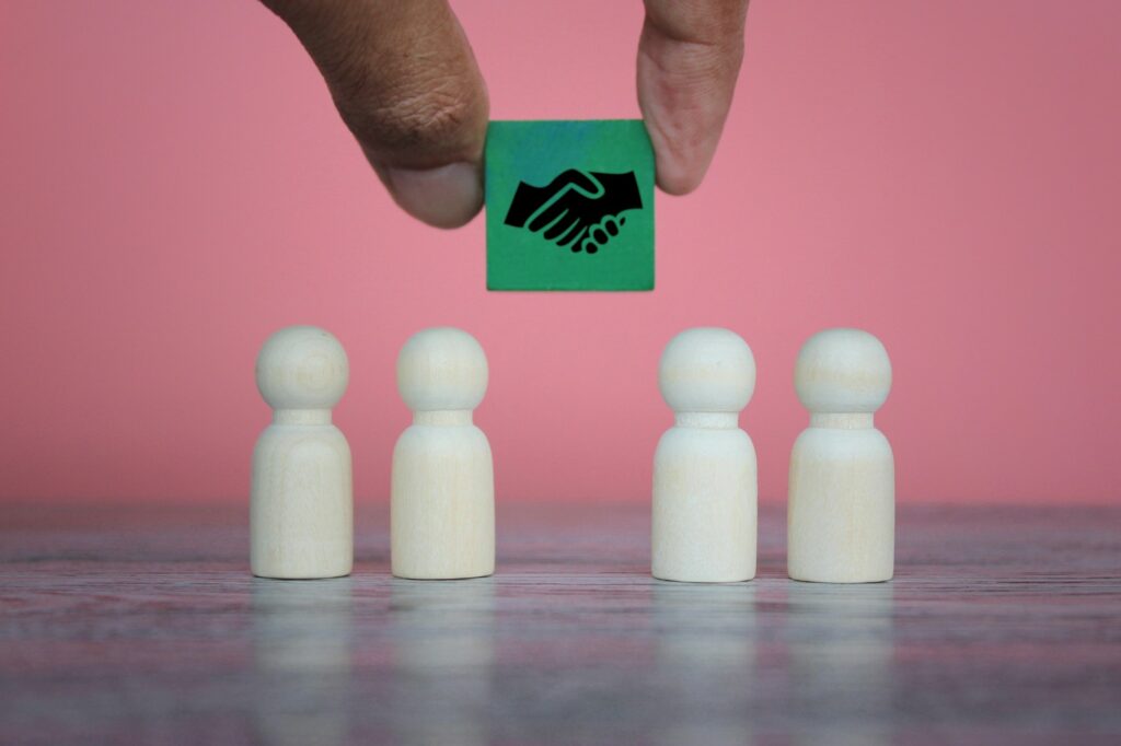 Wooden dolls and wooden cube with handshake icon